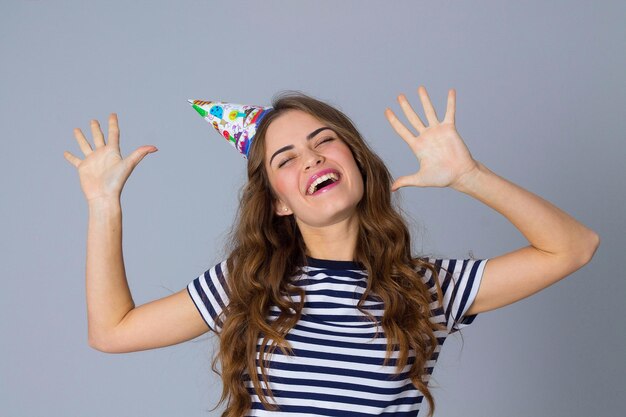 Foto mujer sonriente joven en camiseta despojada y gorra de celebración mostrando los pulgares hacia arriba