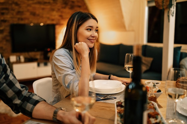 Mujer sonriente joven durante la cena en la mesa de comedor