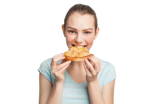 Mujer sonriente joven comiendo un trozo de pizza, aislado en blanco