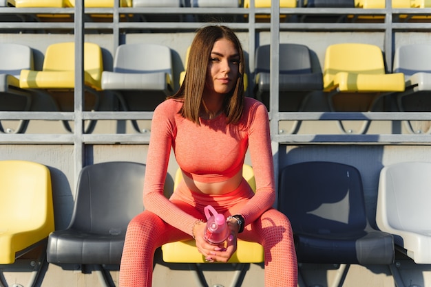 Mujer sonriente joven descansando después de un entrenamiento físico activo.