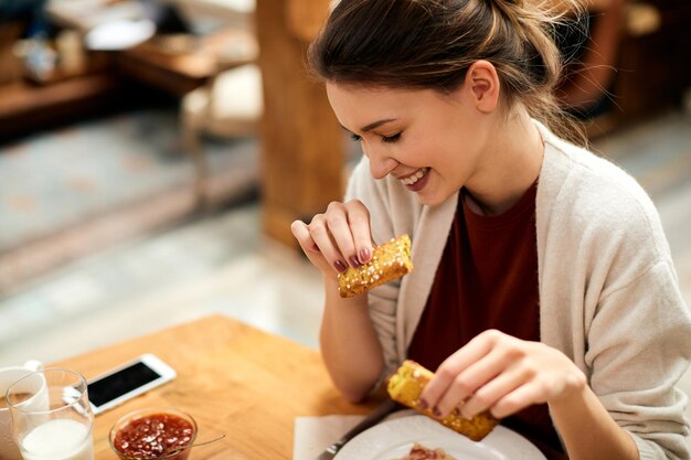 Mujer sonriente joven disfrutando del desayuno en casa