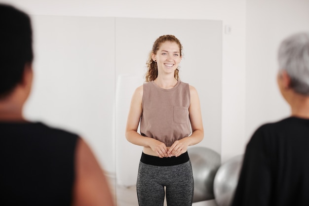 Mujer sonriente joven con entrenamiento deportivo para personas como entrenador en el gimnasio