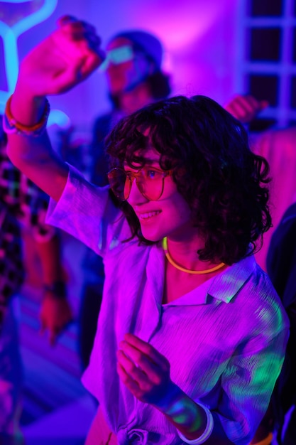 Foto mujer sonriente joven con el pelo rizado oscuro bailando en la fiesta en casa