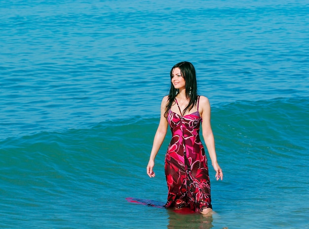 Mujer sonriente joven de pie en las olas del mar