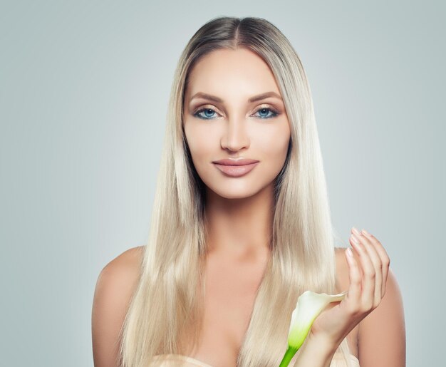 Mujer sonriente joven con piel limpia Cabello sano y flores blancas en sus manos Tratamiento facial Cosmetología Belleza Cuidado de la piel y spa