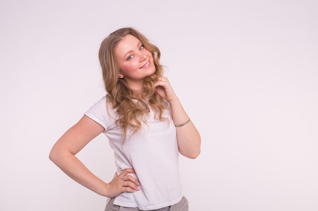 Mujer sonriente joven posando sobre blanco con espacio de copia