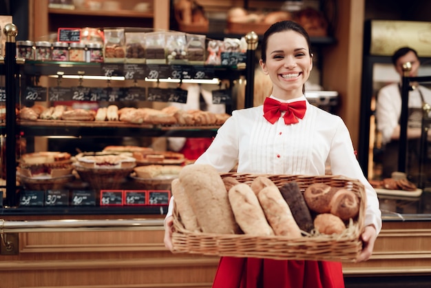 Foto mujer sonriente joven que se coloca con pan en panadería.