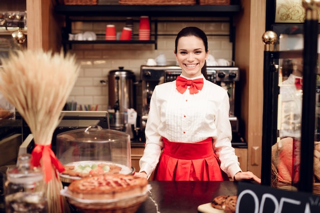 Mujer sonriente joven que se coloca en panadería moderna.