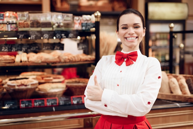 Mujer sonriente joven que se coloca en panadería moderna.