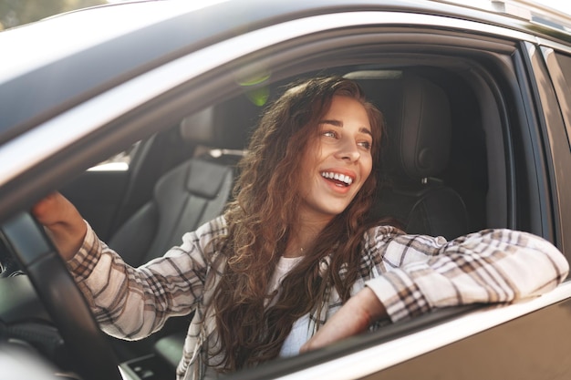 Foto mujer sonriente joven que conduce un coche en la ciudad