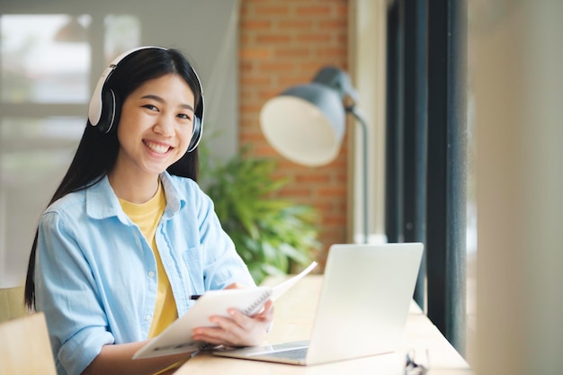 Mujer sonriente joven que estudia y que sostiene el papeleo que mira la cámara