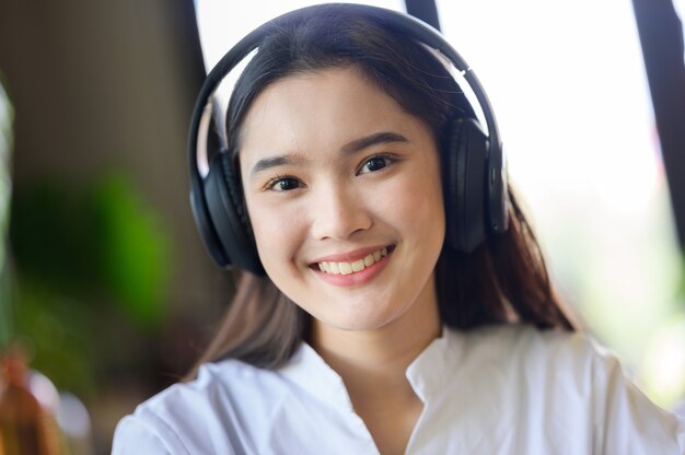 Mujer sonriente joven relajarse y escuchar música con auriculares