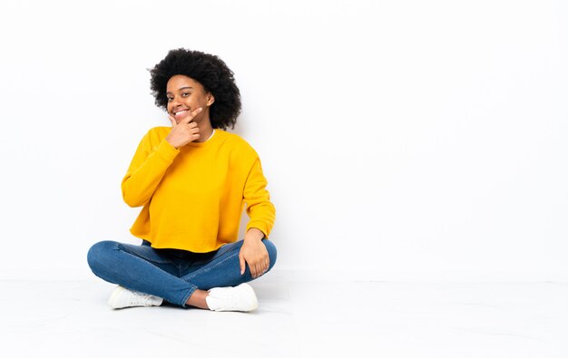 Mujer sonriente joven sentada en el suelo