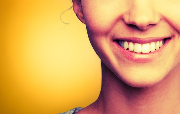 Mujer sonriente joven sobre fondo amarillo