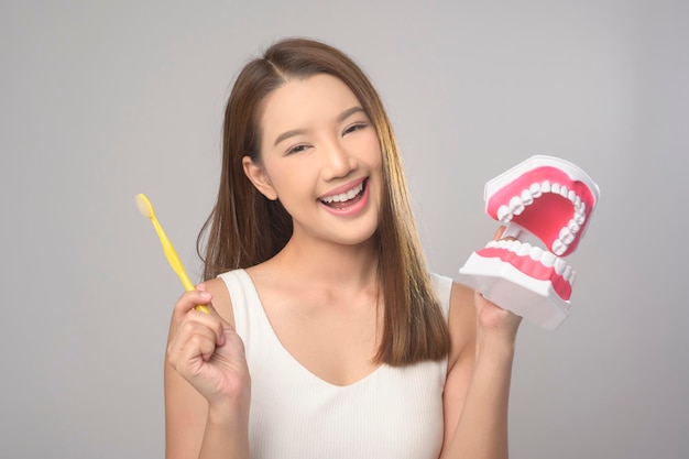 Mujer sonriente joven sosteniendo cepillo de dientes sobre estudio de fondo blanco