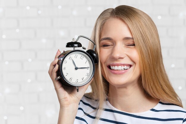 La mujer sonriente joven sostiene el reloj negro