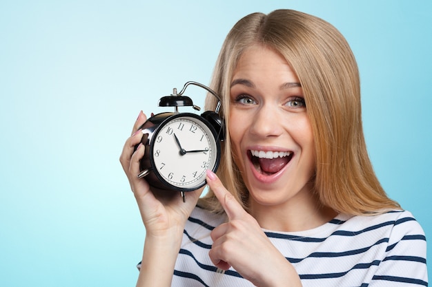 La mujer sonriente joven sostiene el reloj negro