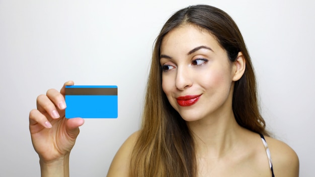 Mujer sonriente joven con tarjeta de crédito y mirando