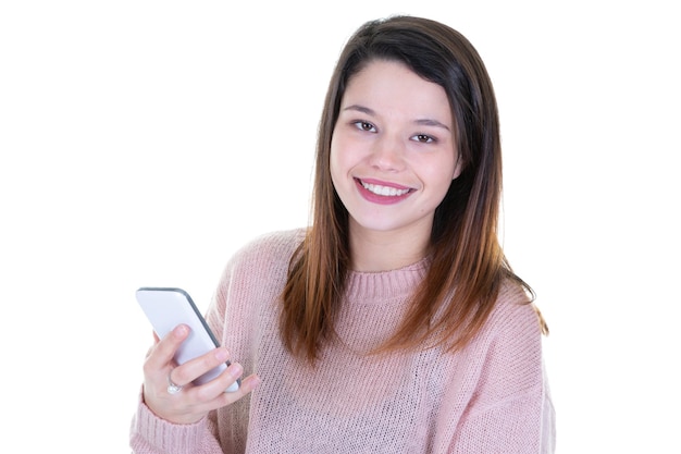 Mujer sonriente joven con teléfono móvil de mensajes de texto contra el fondo blanco.