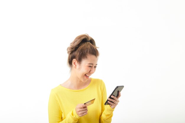 Mujer sonriente joven con teléfono y número de tarjeta de crédito para comprar en línea