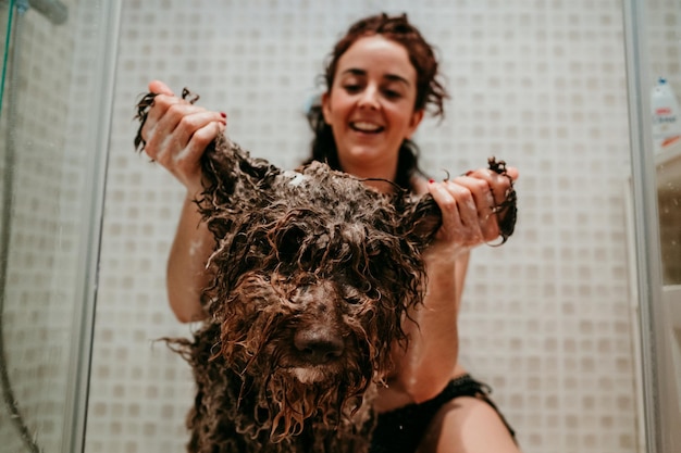 Foto una mujer sonriente lavando un perro.