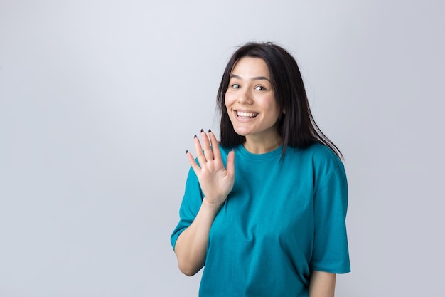 Mujer sonriente levantó la palma de la mano hacia arriba y hacia adelante como saludando.