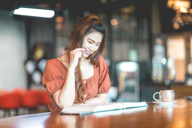 Mujer sonriente leyendo un libro en un café