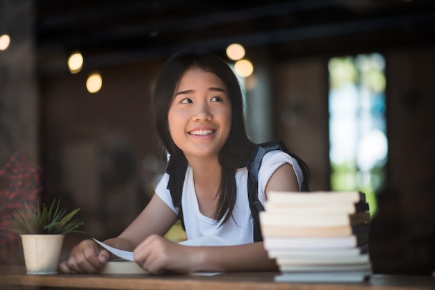 Mujer sonriente con un libro sentada en una cafetería