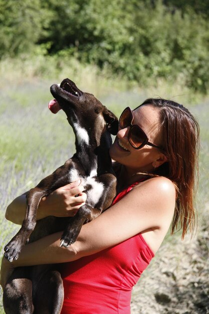 Mujer sonriente llevando al perro al aire libre