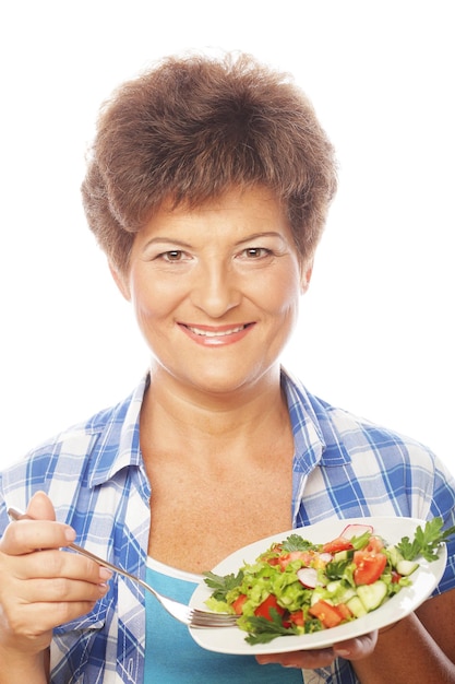 Foto mujer sonriente madura comiendo ensalada