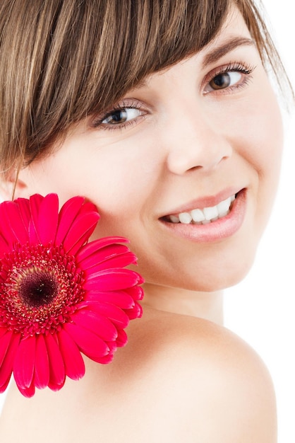 Mujer sonriente con maquillaje creativo y flor de gerbera sobre fondo de color