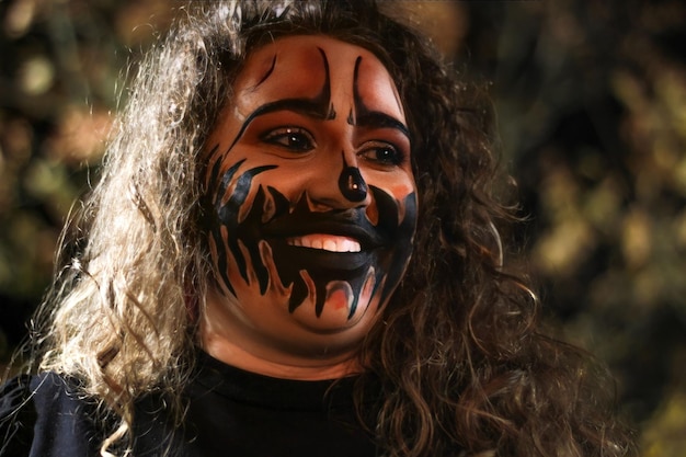 Mujer sonriente con maquillaje de noche de halloween Retrato de una mujer con maquillaje de noche de halloween al aire libre