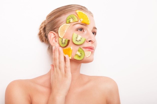 Mujer sonriente con máscara de frutas en su rostro aislado