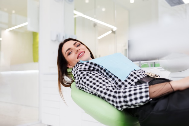 La mujer sonriente miente en la silla del consultorio dental