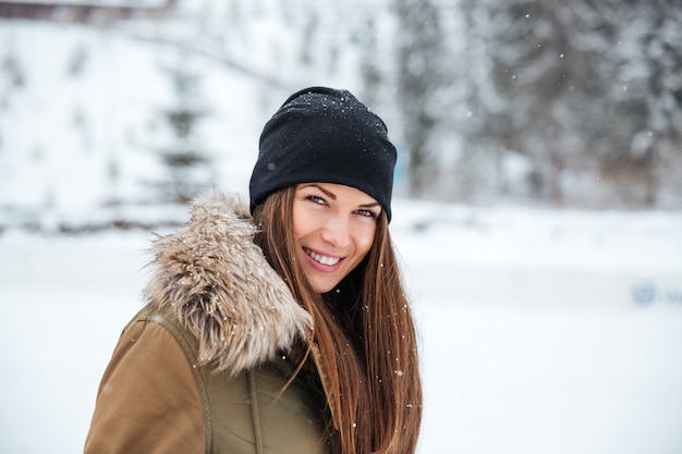 Mujer sonriente mirando a la cámara al aire libre con nieve