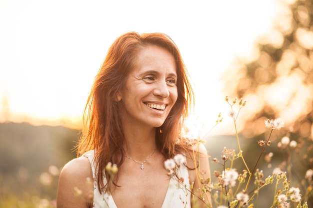 Mujer sonriente mirando hacia el cielo durante la puesta de sol