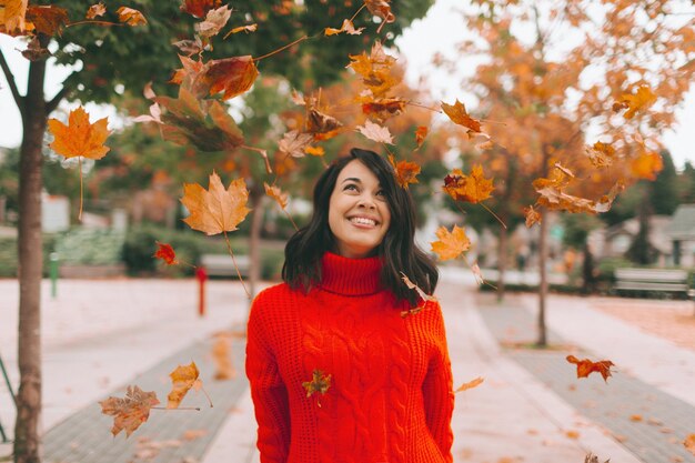 Mujer sonriente mirando las hojas mientras está de pie en el sendero durante el otoño