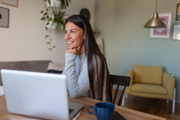 Mujer sonriente mirando hacia otro lado mientras está sentada en casa