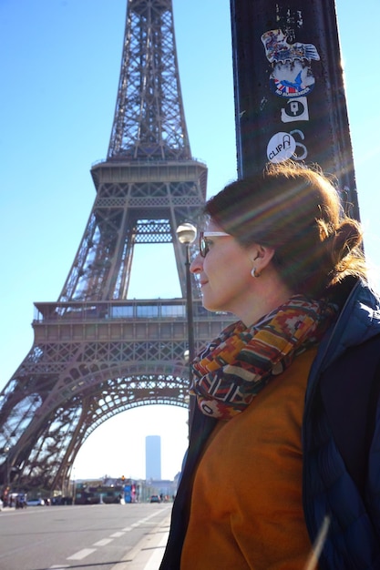 Mujer sonriente mirando hacia la Torre Eiffel