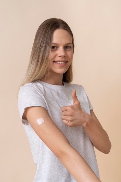 Foto mujer sonriente mostrando el brazo con la etiqueta engomada después de recibir una vacuna