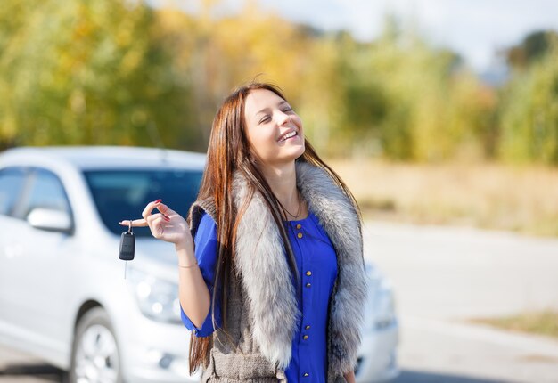 Mujer sonriente mostrando las llaves del coche nuevo