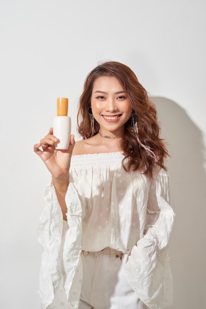 Mujer sonriente mostrando productos para el cuidado de la piel