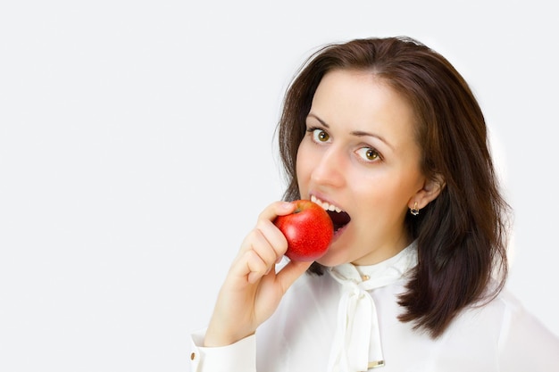 Mujer sonriente muerde la manzana roja.