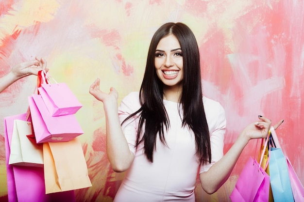 Mujer sonriente muy sexy con bolsas de la compra en colores de fondo