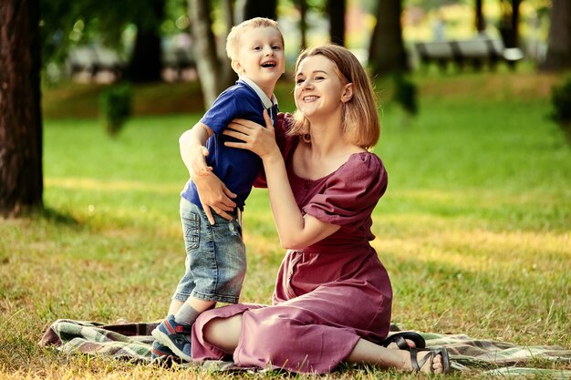 Mujer sonriente con niño caminar en parque público