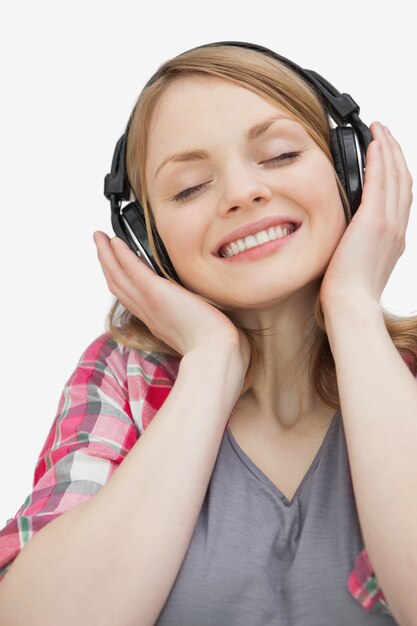 Mujer sonriente con los ojos cerrados escuchando música