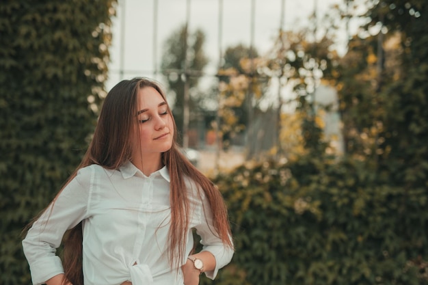 Foto mujer sonriente con los ojos cerrados de pie al aire libre.