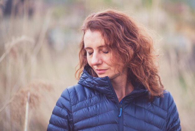 Mujer sonriente con los ojos cerrados de pie al aire libre