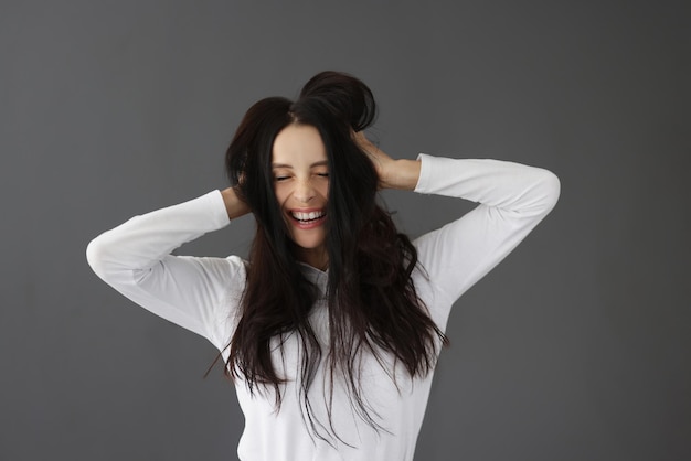 Mujer sonriente con los ojos cerrados sobre fondo gris concepto de emociones femeninas