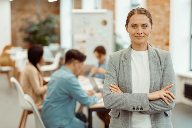 Foto mujer sonriente parada en un espacio de coworking y juntando sus manos